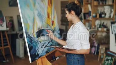 女艺术家集中精力在画美丽的画海和画船上，在画室里独自画油画